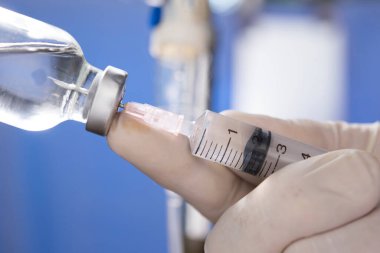 Doktor eli şırıngayı ilaç şişesine enjekte ediyor.