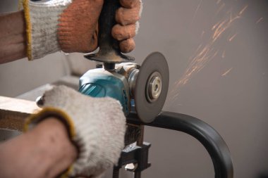 İnsan elleri elektrikli testere ile demir boru kesiyor.