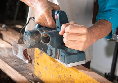 carpenter using electric wood plane.