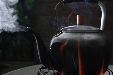 Su, odun ateşinde alüminyum sığırlarda kaynıyor.