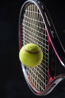 closeup tennis racket with ball isolated black background