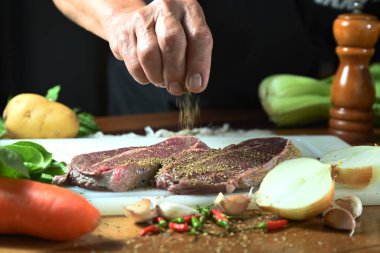 Baharat ve malzemelerle kesilmiş bifteğin yakın plan çekimi.