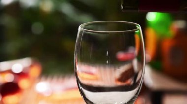 red wine pouring into glass in front of barbecue grill background
