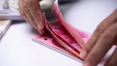 Tezgahtaki Çin banknotlarını sayan eller.