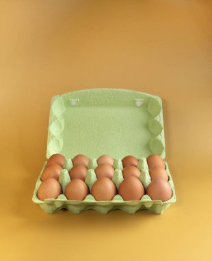 İzole edilmiş sarı arka planda tavuk yumurtası paketleme