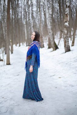 Pavloposadsky eşarplı bir kız. Kız kış ormanında yürüyor. Mavi eşarp. Mavi Pavloposadsky eşarbı.