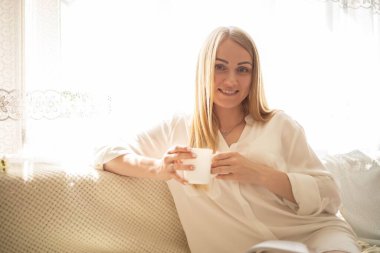 Kadın uyandı ve kahve içiyor. Sabah bir fincan kahveyle