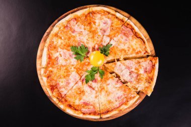 Yuvarlak pizza ve siyah arka planda tahta bir tahta üzerinde yumurta.