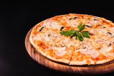 Siyah arka planda tahta üzerinde mantarlı İtalyan pizzası.