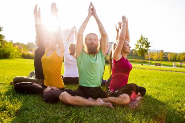 Nilüfer çiçekli bir grup insan parkta yeşil bir çimenlikte poz veriyor.