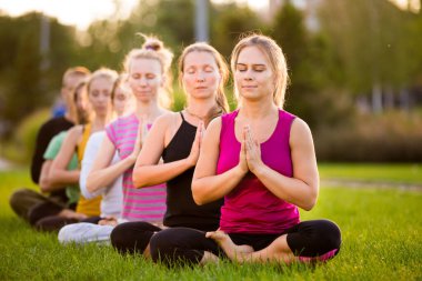 Nilüfer çiçekli bir grup insan parkta yeşil bir çimenlikte poz veriyor.