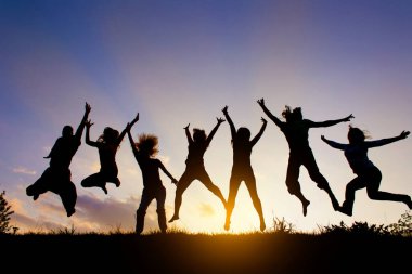 Bir grup insan gün batımına karşı atlıyor.