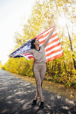 Amerikan bayrağıyla gülümseyen genç kadın.