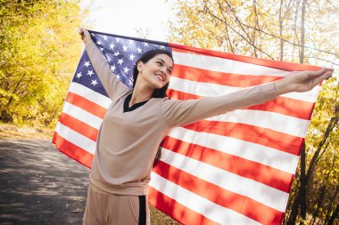 Amerikan bayrağıyla gülümseyen genç kadın.
