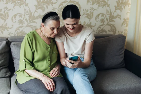 Grandmother Granddaughter Look Smartphone While Sitting Couch Looking Photos Phone Royalty Free Stock Images