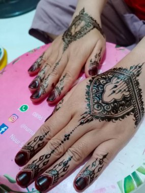 Elinde dövme ve kına seçici odaklı parlak bir manikür var.