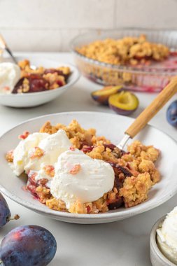 Meyve parçacıkları. Lezzetli kahvaltı için beyaz mermer masada kaşıkları olan vanilyalı dondurmalı erikli turta. Dikey yönelim