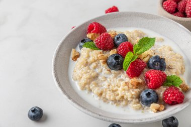 Taze yaban mersini, ahududu, ceviz ve naneli Quinoa lapası beyaz arka planda. Kapat. sağlıklı diyet kahvaltı
