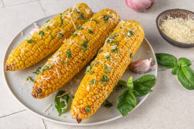 Koçanda tereyağı, parmesan peyniri ve fesleğenle ızgara mısır. Kapat. sağlıklı vejetaryen yemekleri