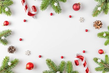 Noel kompozisyonu. Köknar ağacından yapılmış çerçeve, şenlikli süsler, beyaz arka planda kırmızı böğürtlenler. Düz yatıyordu. Kopyalama alanı olan üst görünüm. Kış tatili kavramı