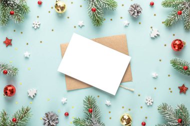 Kar köknar ağacından yapılmış çerçevede Noel tebrik kartı, mavi arka planda şenlik süsleri. Düz yatıyordu. Model yap. Kopyalama alanı olan üst görünüm. Kış tatili daveti