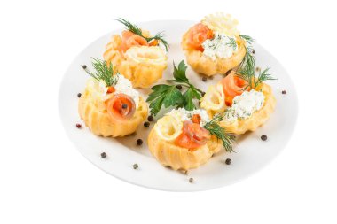Ziyafet atıştırmalıkları. Yumuşak peynir ve somonla doldurulmuş profiteroller beyaz arka planda izole edilmiş bir tabakta. Tatil partisi aperatifleri..