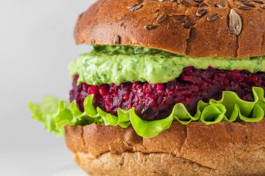 Vejetaryen burgerin yanına pancar sosu, avokado sosu ve beyaz arka planda salata koy. Sağlıklı vejetaryen gıda konsepti