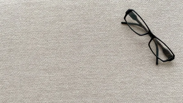 Reading glasses folded up in corner on background pattern in closeup