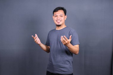 Genç yakışıklı Asyalı adam gri arka planda gülümsüyor rahat ve neşeli başarı ve iyimser