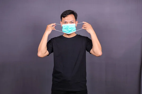 Asian man wearing a mouth protection or mask to prevent getting sick at work. Isolated on Gray Background