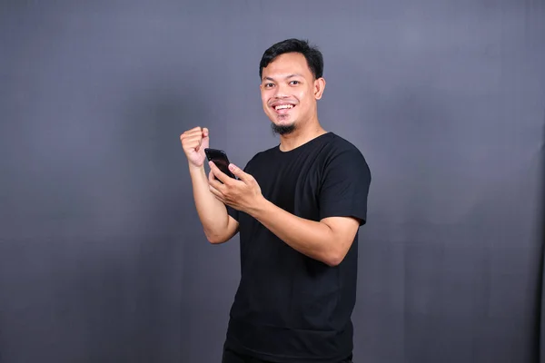 Happy Asian Man Holding Smartphone Winning Prize Isolated Gray Background — Stock Photo, Image