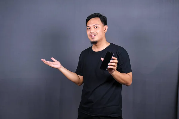 Amazed excited young asian man looking at camera with wow face expression feeling surprised advertising shopping promotion, unbelievable win standing isolated on gray background.