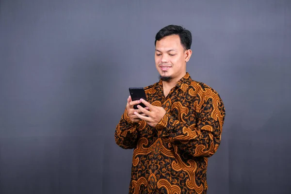 Retrato Asiático Jovem Vestindo Batik Usando Celular Fundo Cinza — Fotografia de Stock