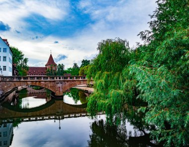 Suda yansıması olan bir nehrin üzerindeki taş köprü.