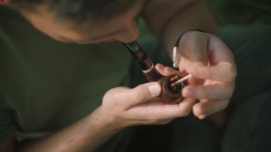 Bir adam kibritle bir boruyu aydınlatıyor.