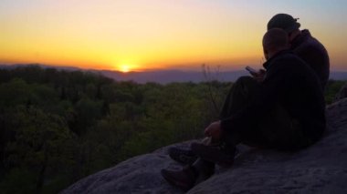 Karpat Dağları 'nda gün batımını izleyen iki adam var. 