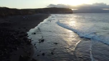 Okyanus dalgalarının gün batımında kayalara çarpan sinematik dron görüntüleri. Azores adaları, Sao Miguel adası. Yüksek kalite 4K görüntü