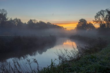 Gökyüzü sisli, soğuk bir kasım sabahı Belçika 'nın başkenti Soygun-Opera-den-Berg' de güneşin ateşiyle aydınlanıyor gibi görünüyor..