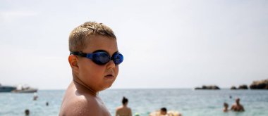 Denizdeki çocuk. Sudan çıktı, ıslandı, gözlük takıyor..