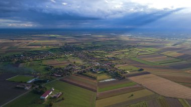 Gökyüzünde dramatik renkler olan ovadaki köyün panoramik hava görüntüsü. Bir fırtına yaklaşıyor.