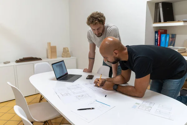 Two young architects working in their studio on a project. They have a new client and they work together to offer him the new house.
