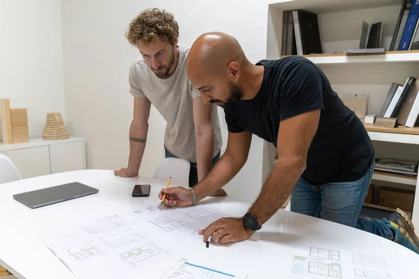 Two young architects working in their studio on a project. They have a new client and they work together to offer him the new house.