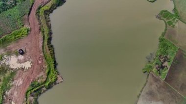 Pirinç tarlalarının ortasında bir göl, Kızıl Toprak kazı projesi için eski bir göl. Hava Görünümü 4K Videosu