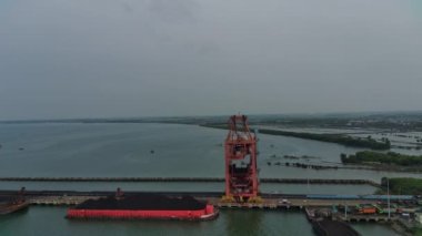 Enerji şirketleri için mavnalardan denize kömür taşıyan ağır ekipman kazıcıları. Hava görünümü.