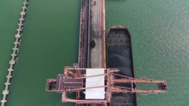 Enerji şirketleri için mavnalardan denize kömür taşıyan ağır ekipman kazıcıları. Hava görünümü.