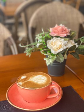 Bir buket çiçeğin yanında bir fincan kahve.