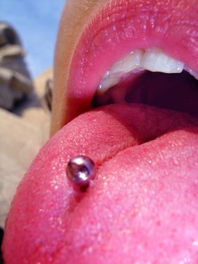 Ağzı açık ve çarpıcı renkleri olan bir dilde piercing ve güzel bir kadın.