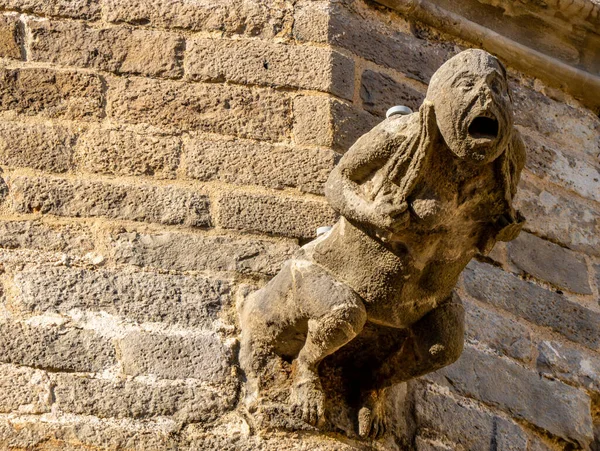 Detail of a gargoyle grabbing its hair and screaming, protruding from the wall of the Barcelona cathedral