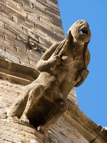 Detail of a gargoyle grabbing its hair and screaming, protruding from the wall of the Barcelona cathedral