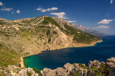 Güney Avrupa 'nın Makarska Riviera kentindeki Adriyatik Denizi üzerinde dağları ve gök mavisi suyu olan harika Hırvat manzarası. Renkli kıyı ve açık mavi gökyüzü, küçük bulutlar. Yüksek kalite fotoğraf.